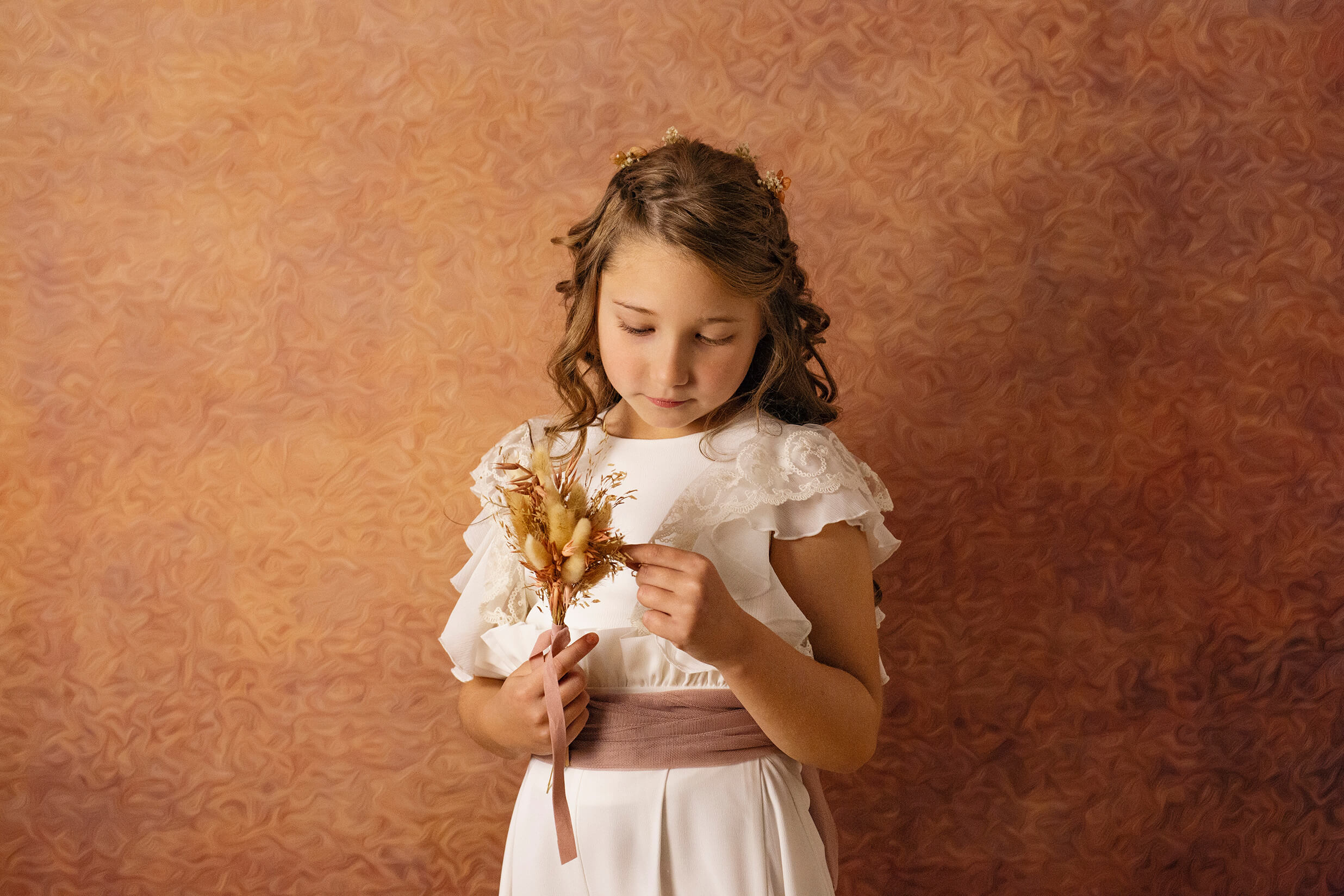 Fotografía de comunión en estudio, niña de comunión cogiendo un ramo de flores 